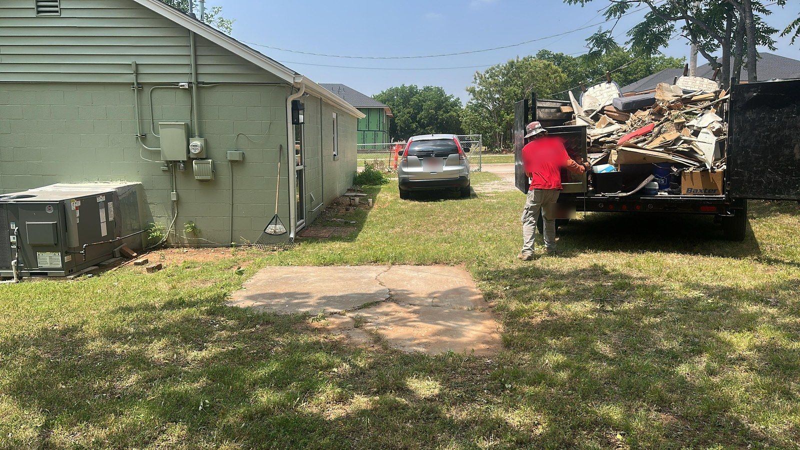 After: the same backyard clear while a crew member finishes loading the trailer