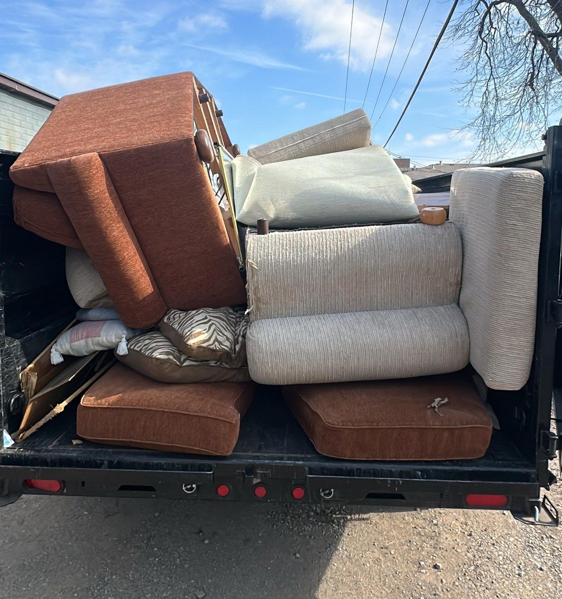 A trailer stacked with an old sofa, cushions and a recliner after a furniture pickup