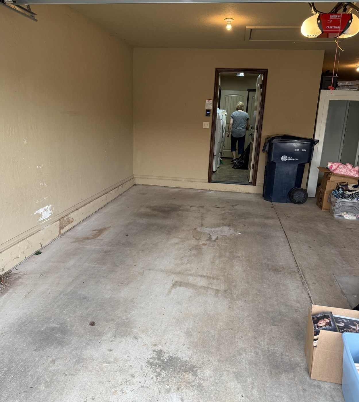 After: the same garage empty and swept, with only a trash cart left