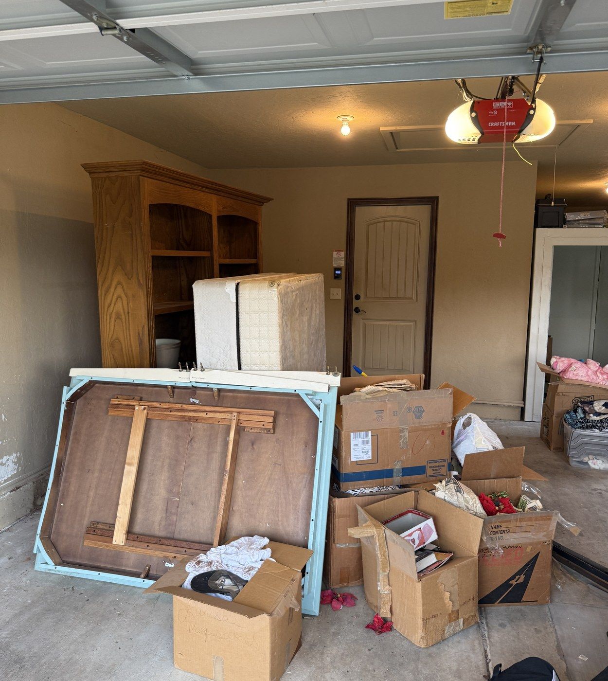 Before: a two-car garage packed with moving boxes, a bookcase, a dresser and a wooden table