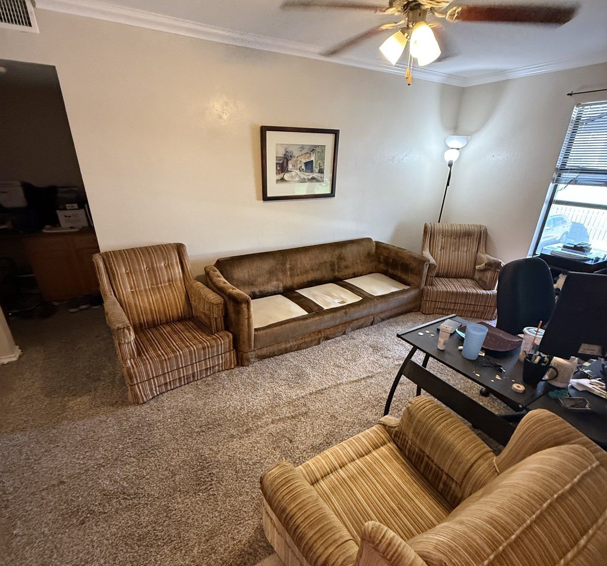 A living room full of dated sofas and armchairs ready to be cleared out