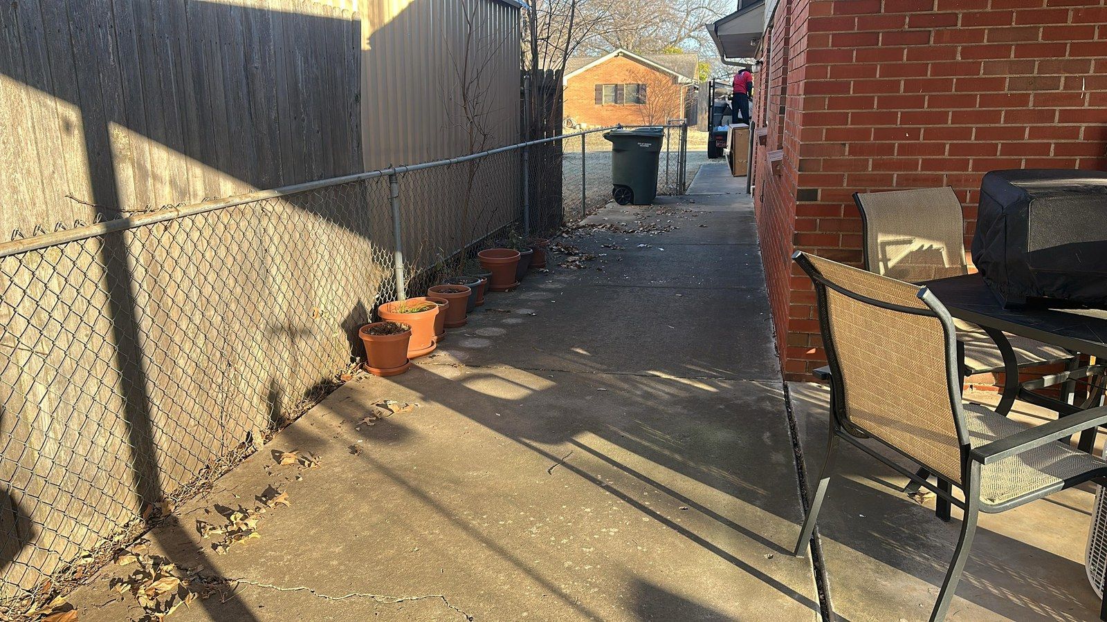 After: the same side yard clear, with only patio chairs and potted plants left