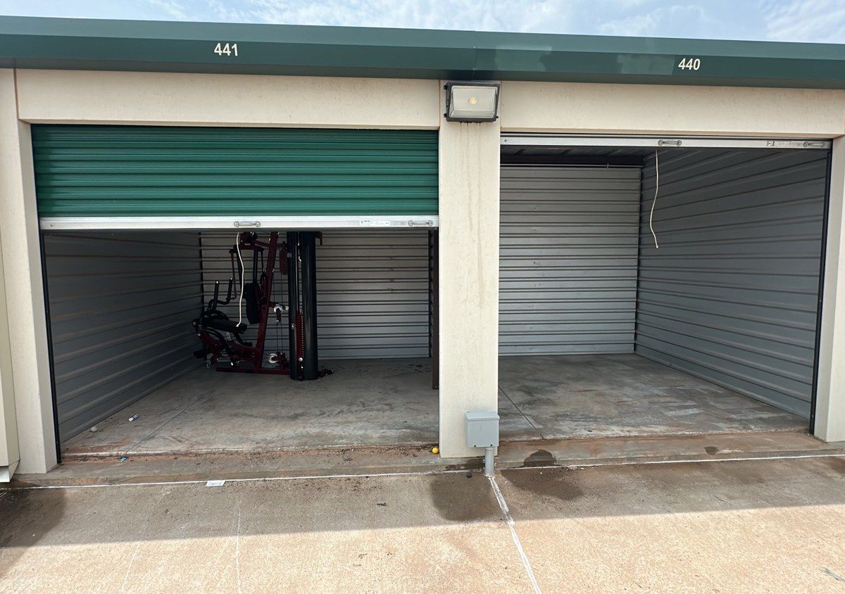 Two self-storage units side by side, one with exercise equipment left inside and one emptied
